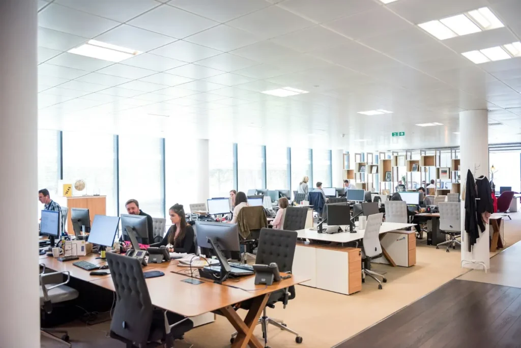Busy open office with employees working at desks, showing high daily foot traffic
