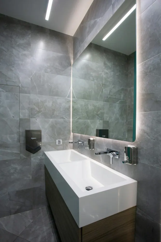 Clean, modern commercial restroom with a wall-mounted sink and soap dispenser