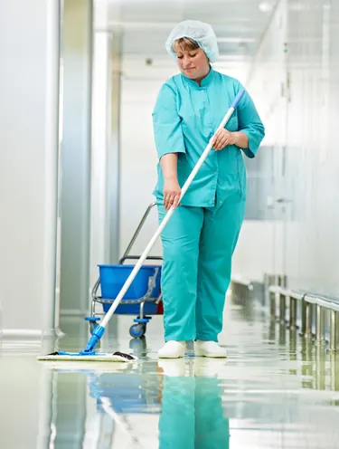 Cleaner mopping a clinic hallway floor